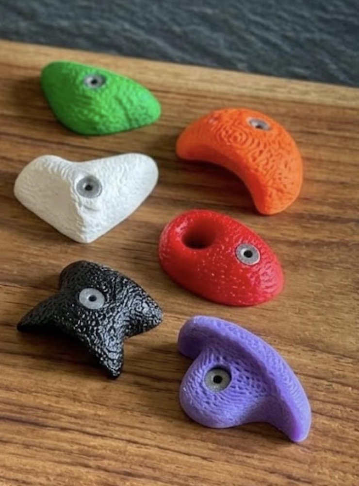 Set of six mini climbing hold magnets in assorted colors on a wood board